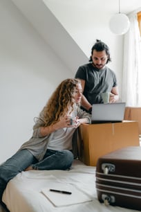 multiracial-couple-watching-laptop-while-sitting-on-bed-with-4245929